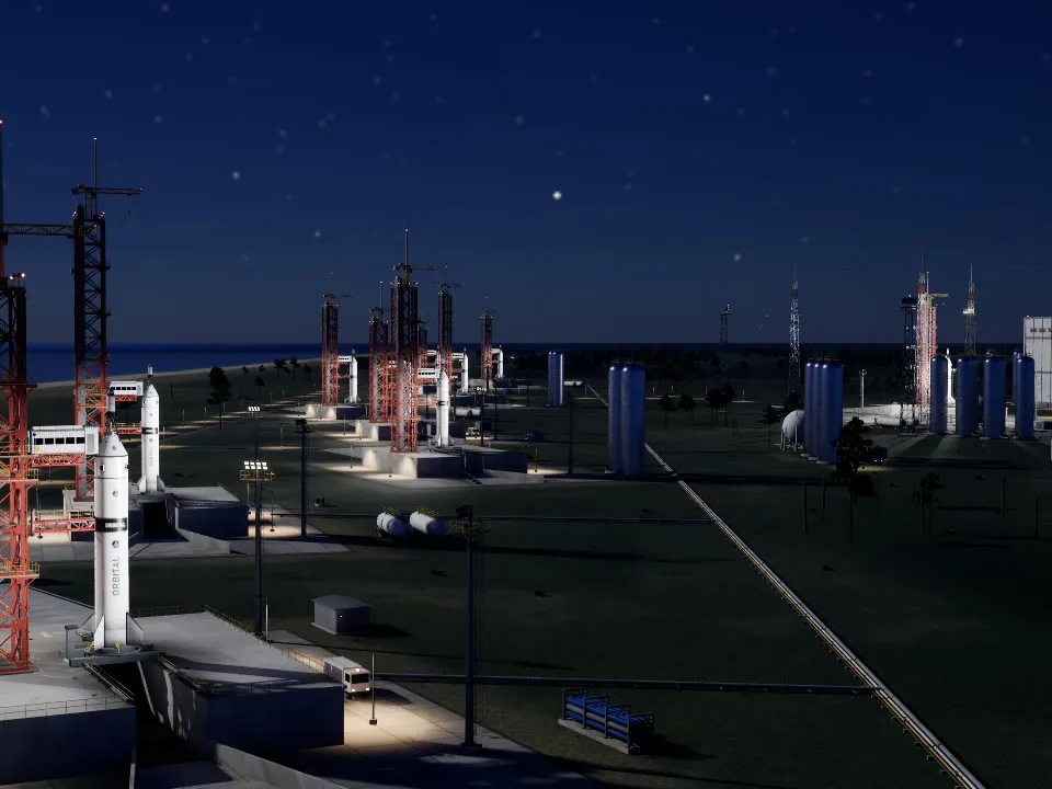 Rockets standing on their pads along the coast at night, lit by floodlights.